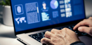 Close-up of hands typing on a laptop with data visualizations on the screen