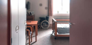 View of a hospital room featuring a patient bed and a wheelchair