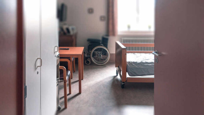 shutterstock2431267537jpg View of a hospital room featuring a patient bed and a wheelchair