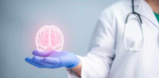 A medical professional holding a glowing digital brain illustration in their hand