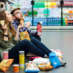 DIY Snack Bars: The Hidden Health Revolution A young couple sitting on the floor of a grocery store enjoying snacks