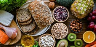 A variety of fresh foods including vegetables, fruits, grains, and proteins arranged on a wooden surface