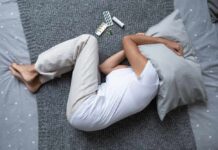 Depression’s Nutritional Link: What You’re Missing! Person lying on a bed with a pillow over their head, surrounded by medication