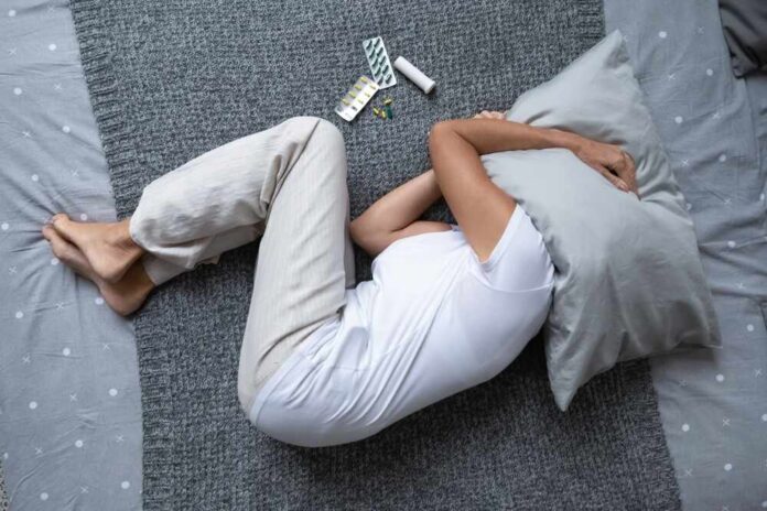 Top,View,Old,Woman,Lying,In,Bed,,Hide,Face,Cover Person lying on a bed with a pillow over their head, surrounded by medication