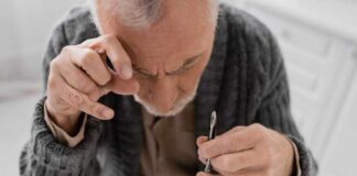 Elderly man focusing intently on a spoon while preparing to eat
