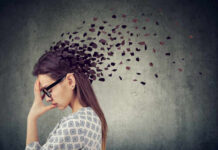 Why Women Are More Prone to Depression and Anxiety A woman with glasses holding her head, with fragments dispersing from her head