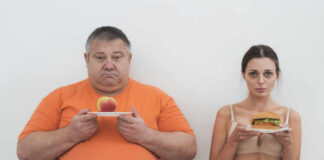 A man holding an apple and a woman holding a hamburger, showcasing contrasting food choices