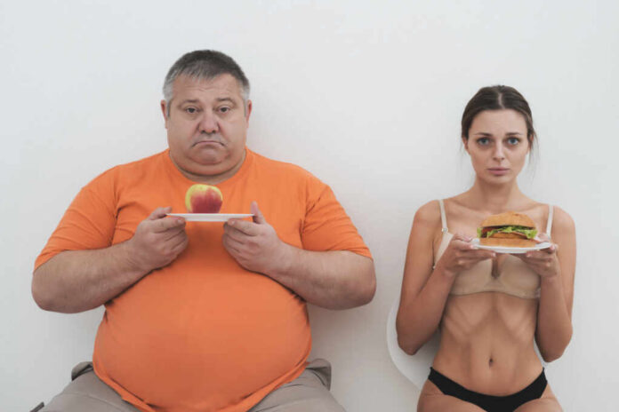 A man holding an apple and a woman holding a hamburger, showcasing contrasting food choices
