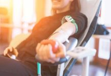 Person donating blood while squeezing a red ball