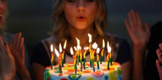 Person blowing out candles on colorful birthday cake