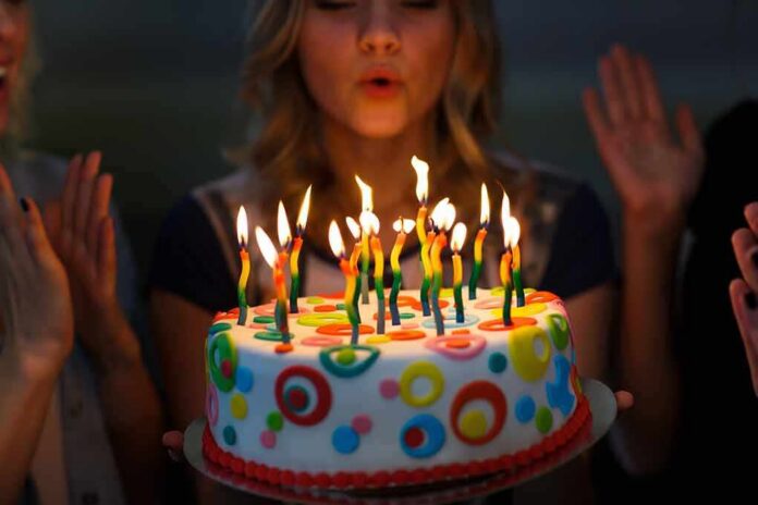 Person blowing out candles on colorful birthday cake