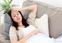 Woman resting on couch with hand on forehead
