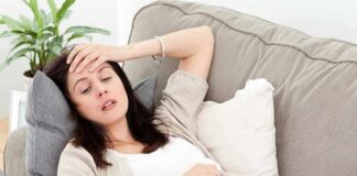 Woman resting on couch with hand on forehead
