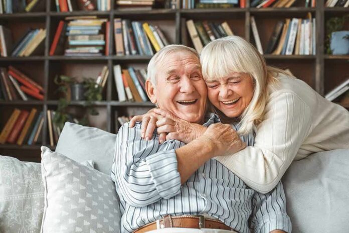 Senior couple hugging and laughing on a couch