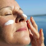 Woman applying sunscreen near water