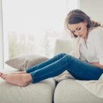4 Morning Habits, Prevent Gut Problems (Gas, Acidity, Bloating) Woman sitting on couch holding her stomach