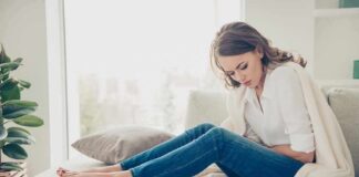 Woman sitting on couch holding her stomach