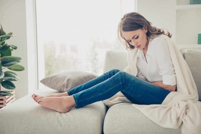 Woman sitting on couch holding her stomach