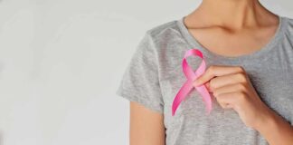 Person holding a pink ribbon on a gray shirt