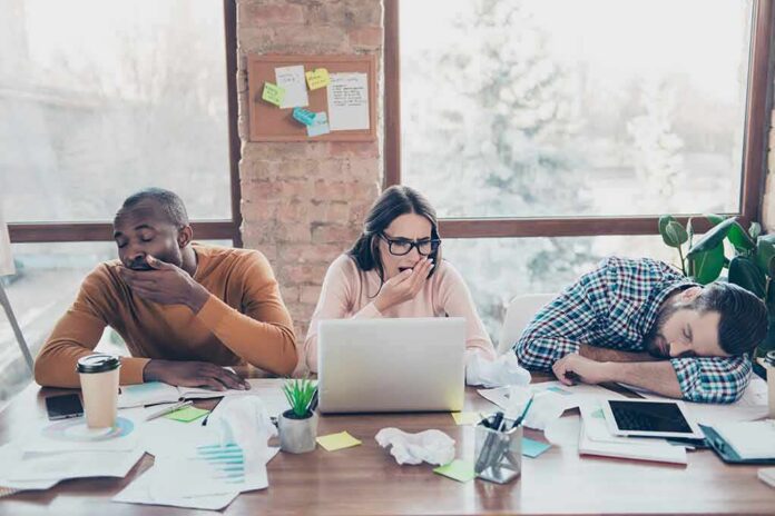 tired coworkers at a cluttered desk