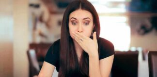 Woman covering mouth while looking at a plate of pasta