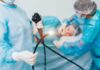 Medical staff preparing endoscope near patient on hospital bed