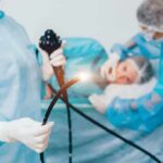 Medical staff preparing endoscope near patient on hospital bed