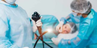 Medical staff preparing endoscope near patient on hospital bed