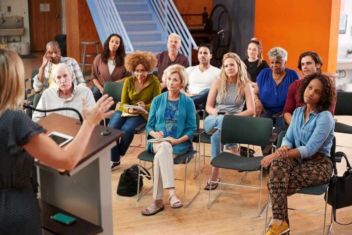 shutterstock_1380362828 Audience listening to a speaker in a small community meeting room