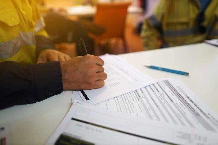 Worker hand filling out forms on a desk