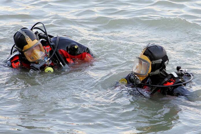 two divers in full-face masks floating in choppy water