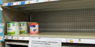 Store shelf with mostly empty baby formula section and limit notice