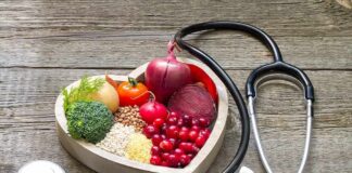 Heart-shaped bowl with fruits, vegetables, grains and a stethoscope