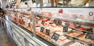 butcher counter with assorted meats in trays behind glass
