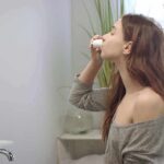 woman in bathroom using nasal spray