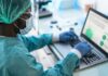 Healthcare worker in PPE using a laptop in a lab