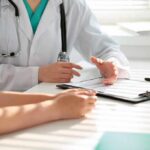 Top Signs of Iron Deficiency and Anaemia Doctor discusses medical notes with patient at a desk